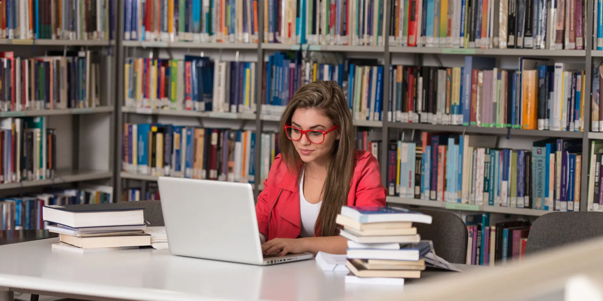 En kvinna sitter i ett bibliotek och studerar