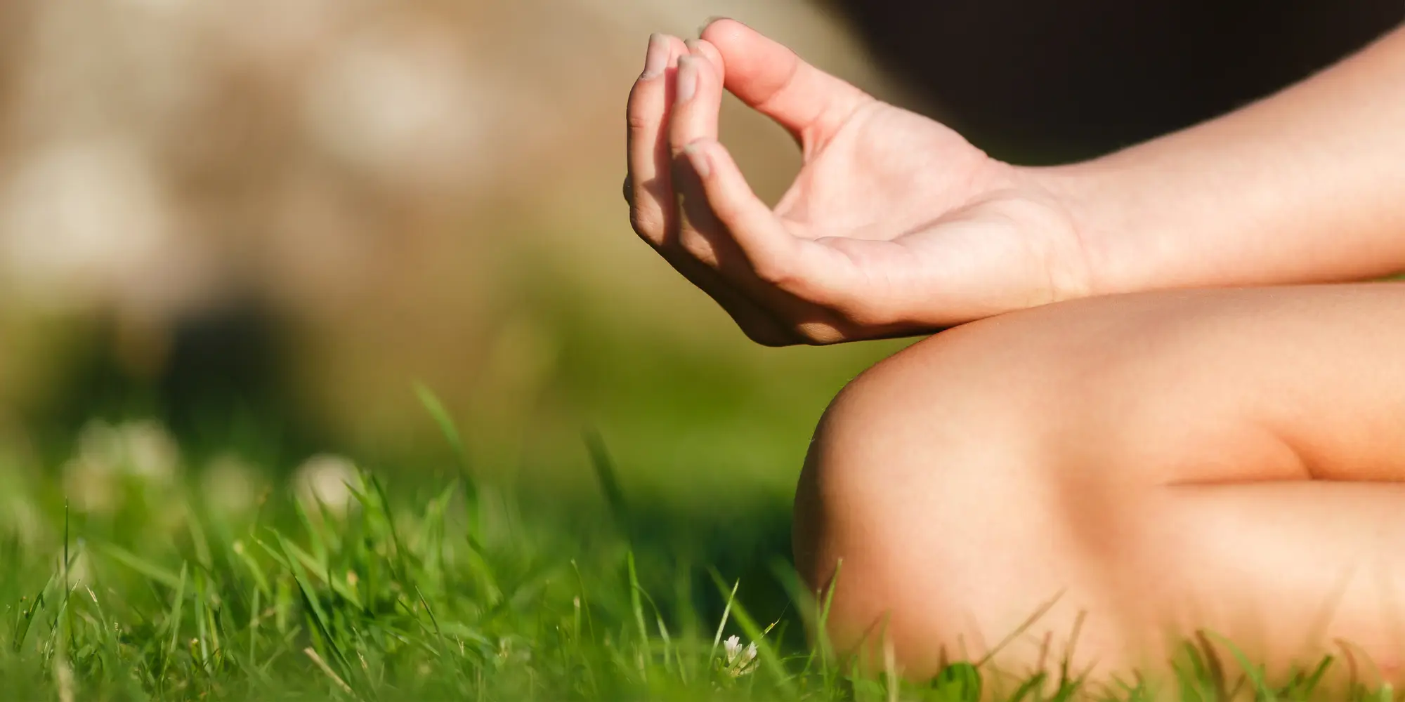 En kvinna praktiserar yoga i gräset