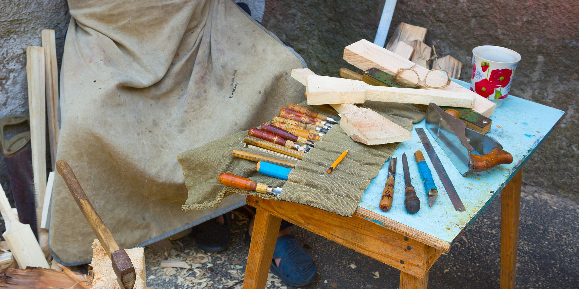 En person sitter vid ett bord med vektyg till träsnideri