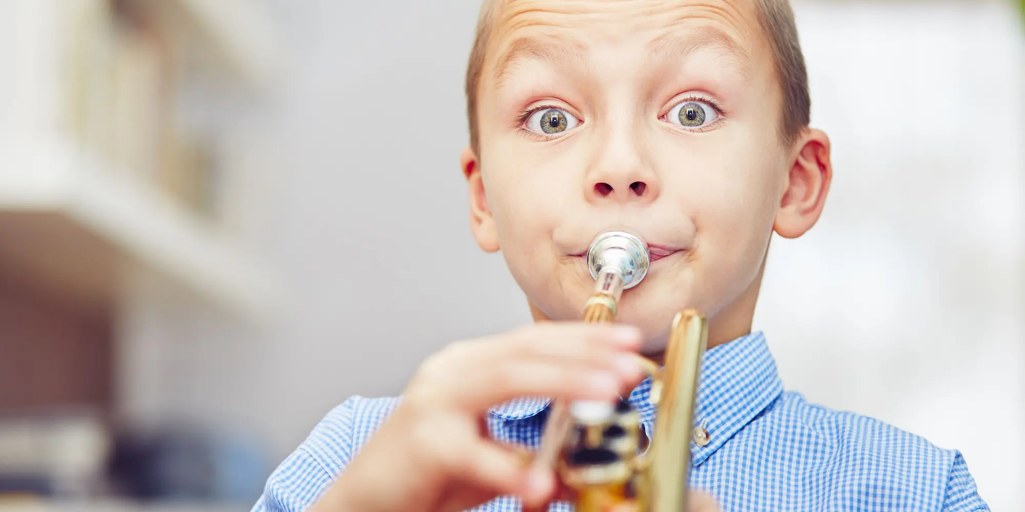 En pojke blåser i en trumpet