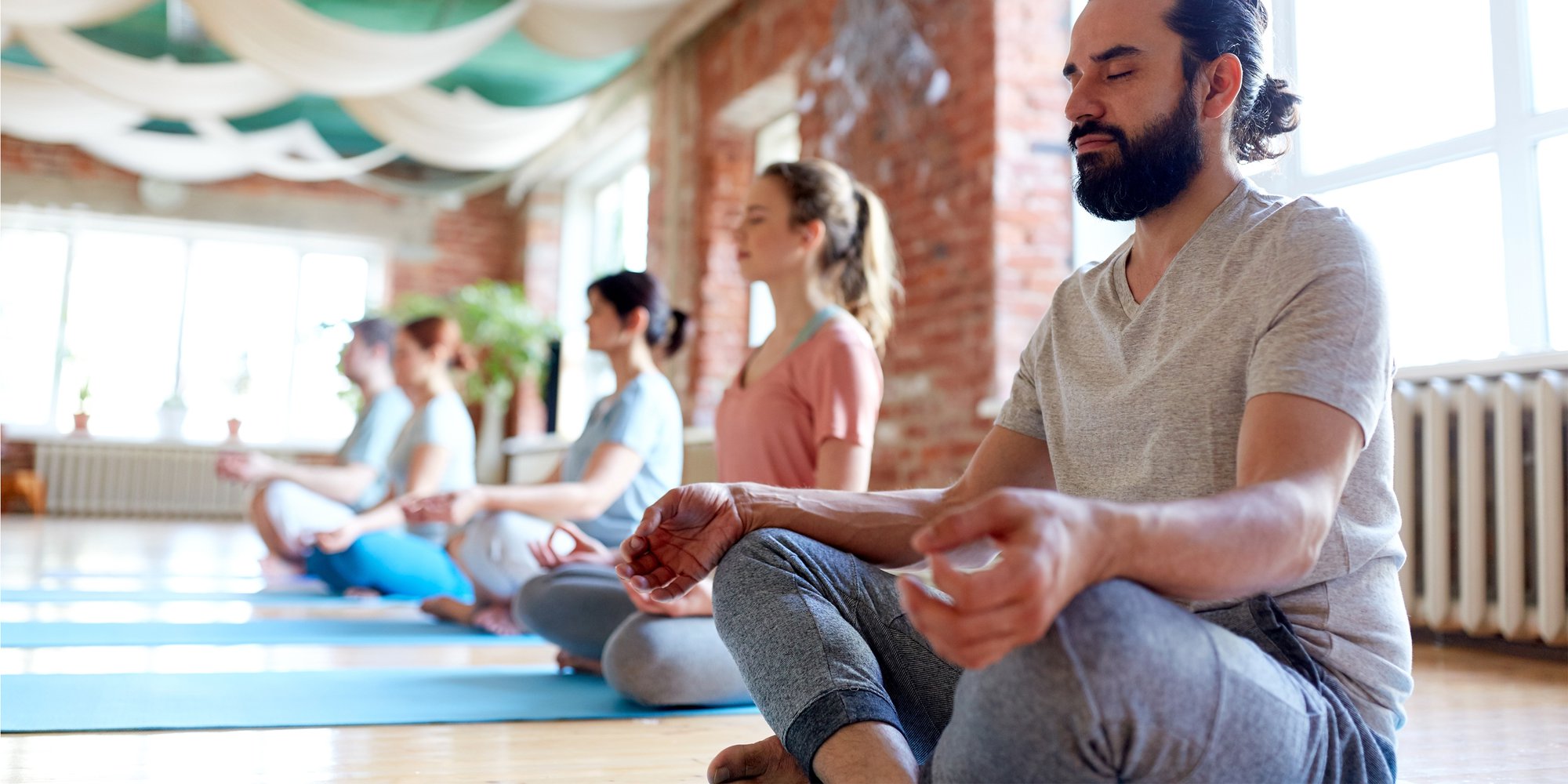 En grupp yogaelever mediterar på yogamatta