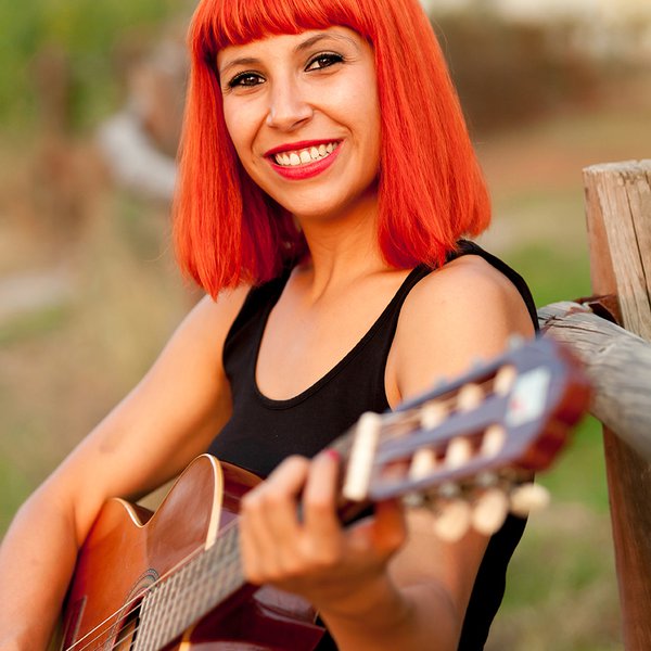 Rödhårig kvinna spelar gitarr.