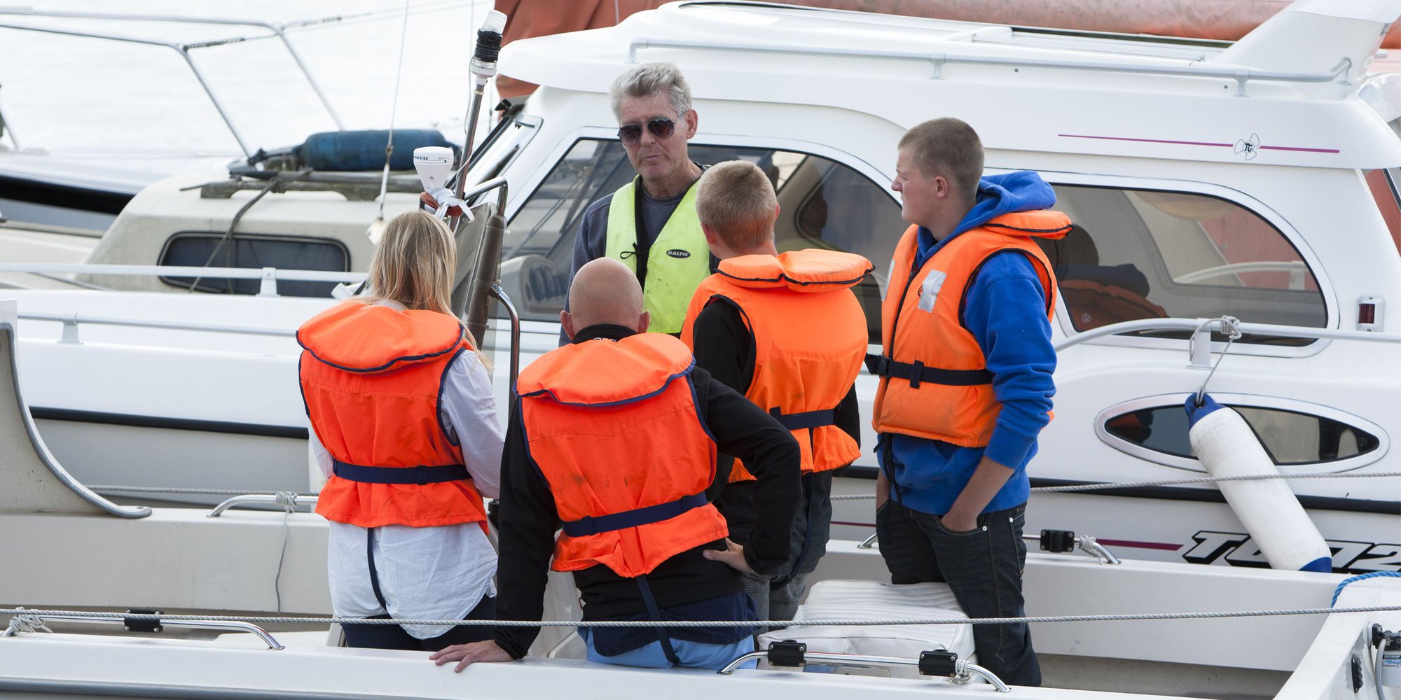 En grupp människor i flytväst kommunicerar med varandra på en båt