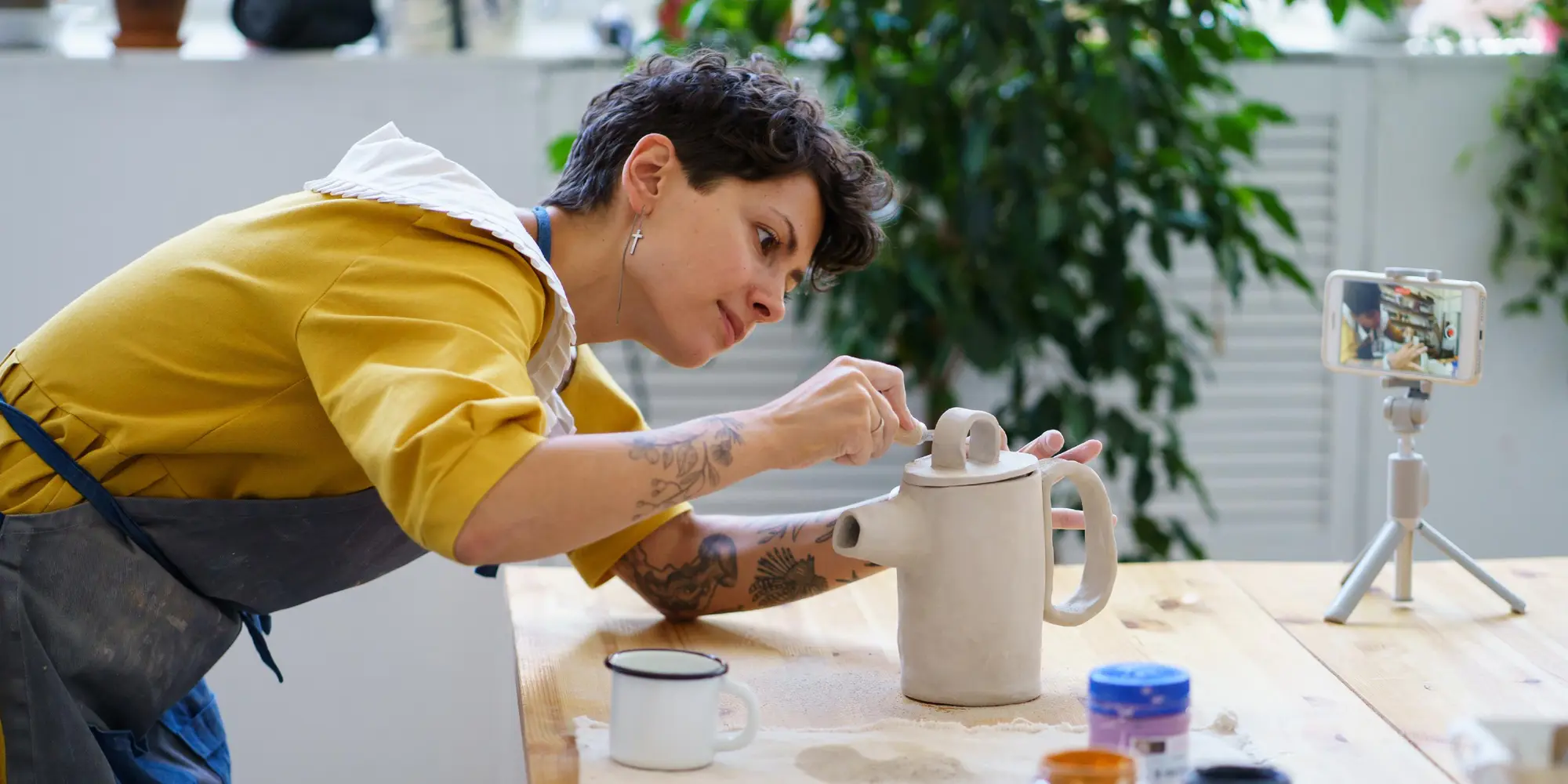 Kvinna filmar sig själv jobbar med keramik