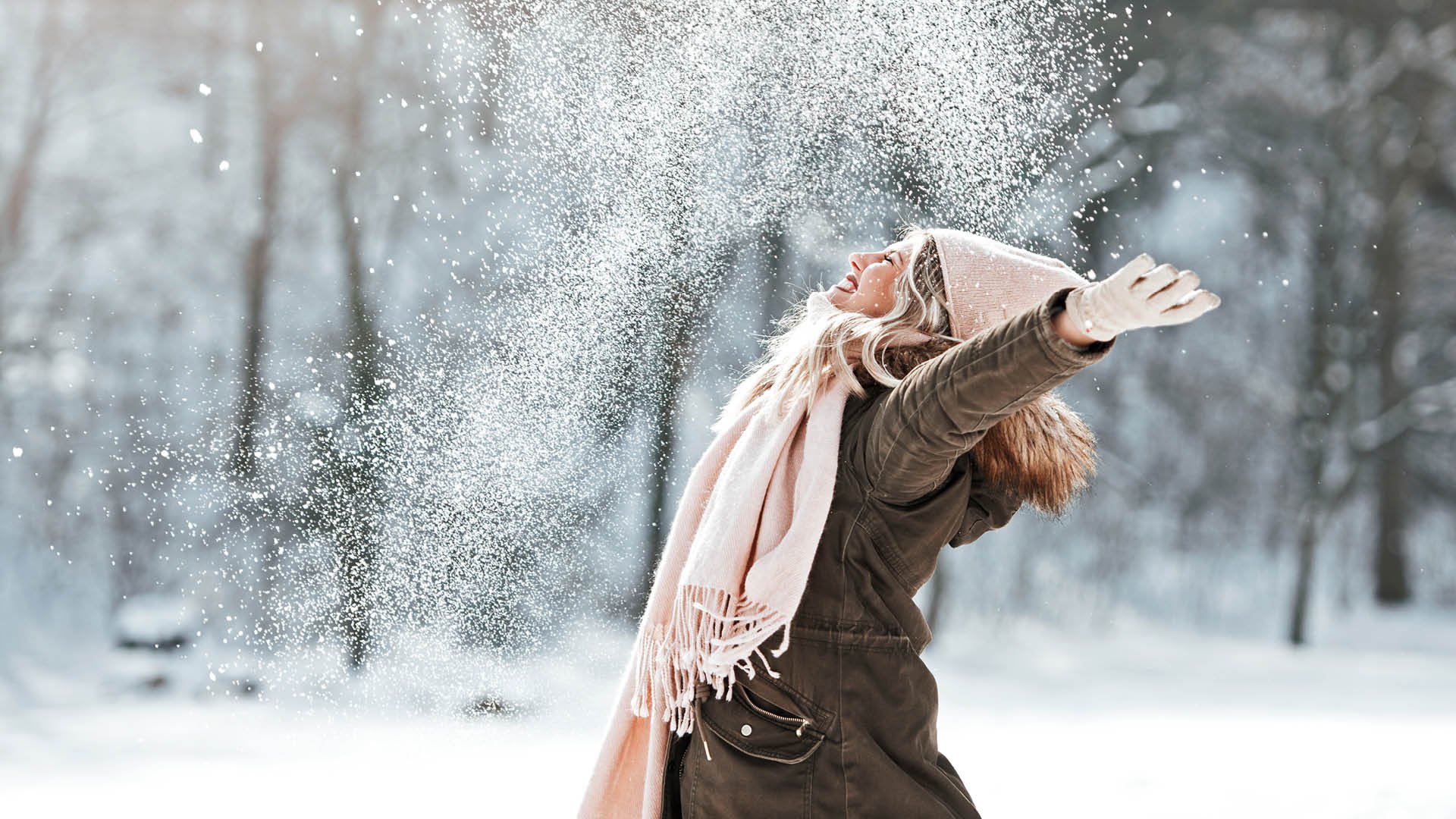 Glad kvinna kastar snö.