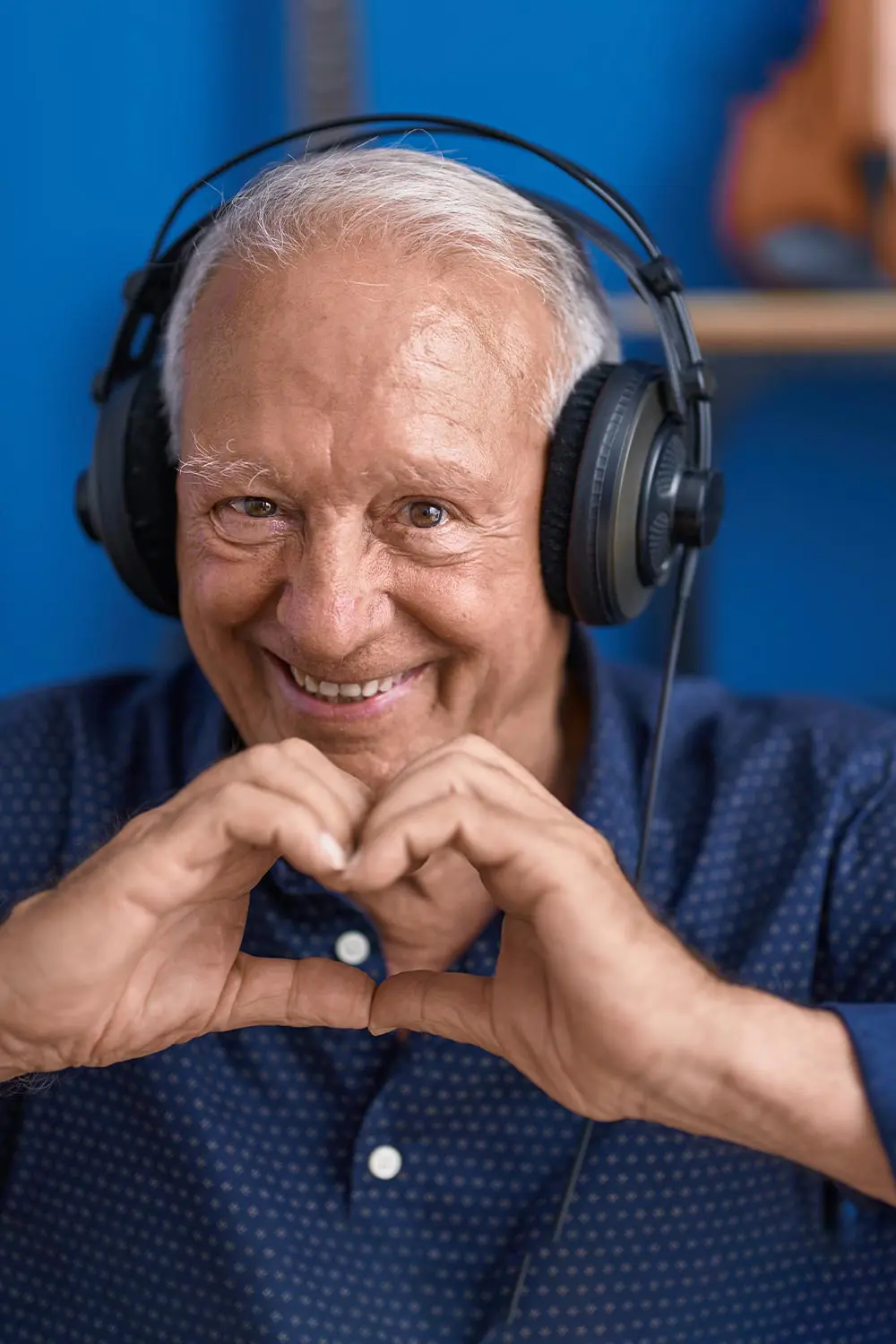 En äldre man i en musikstudio, formar händerna som ett hjärta