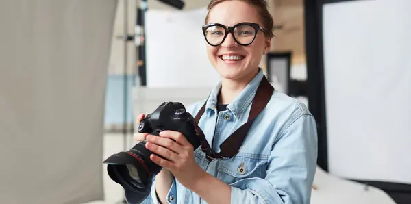 Kvinna håller kamera i fotostudio