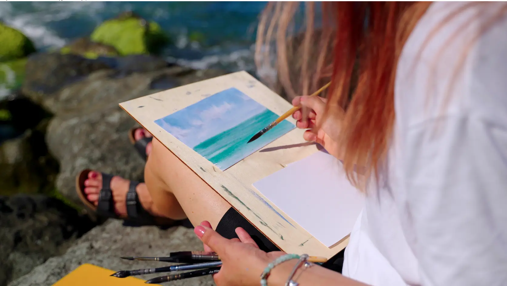 Kvinna målar med akvarell vid havet