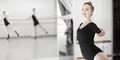 Ung kvinna i svart balettklädsel tränar vid balettstång i en ljus dansstudio.