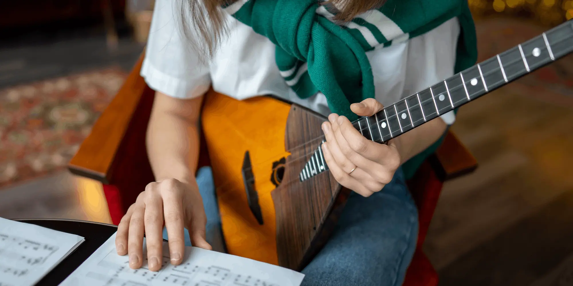 Närbild på en person som spelar balalajka och läser noter