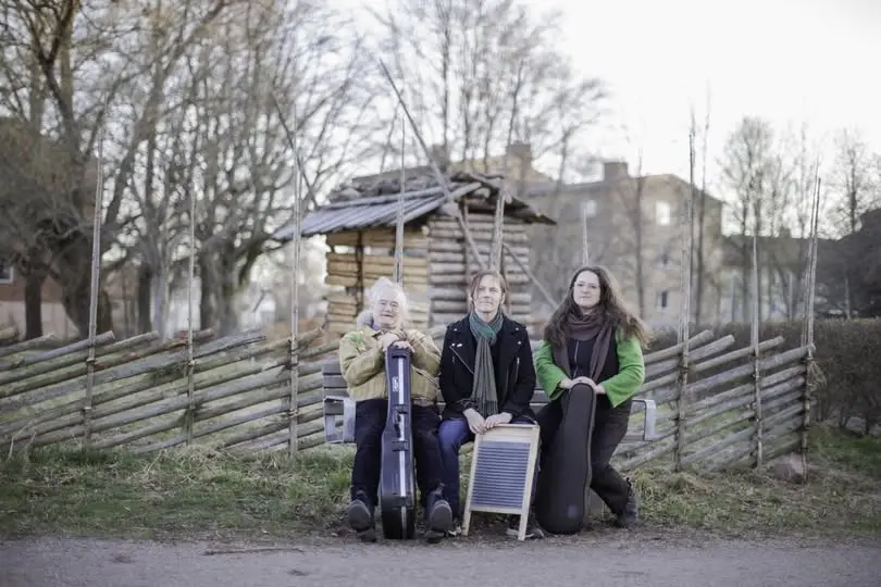 En tri musiker som poserar utomhus