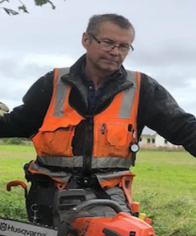 Kursledare Stellan Eriksson står med en motorsåg vid ett träd.