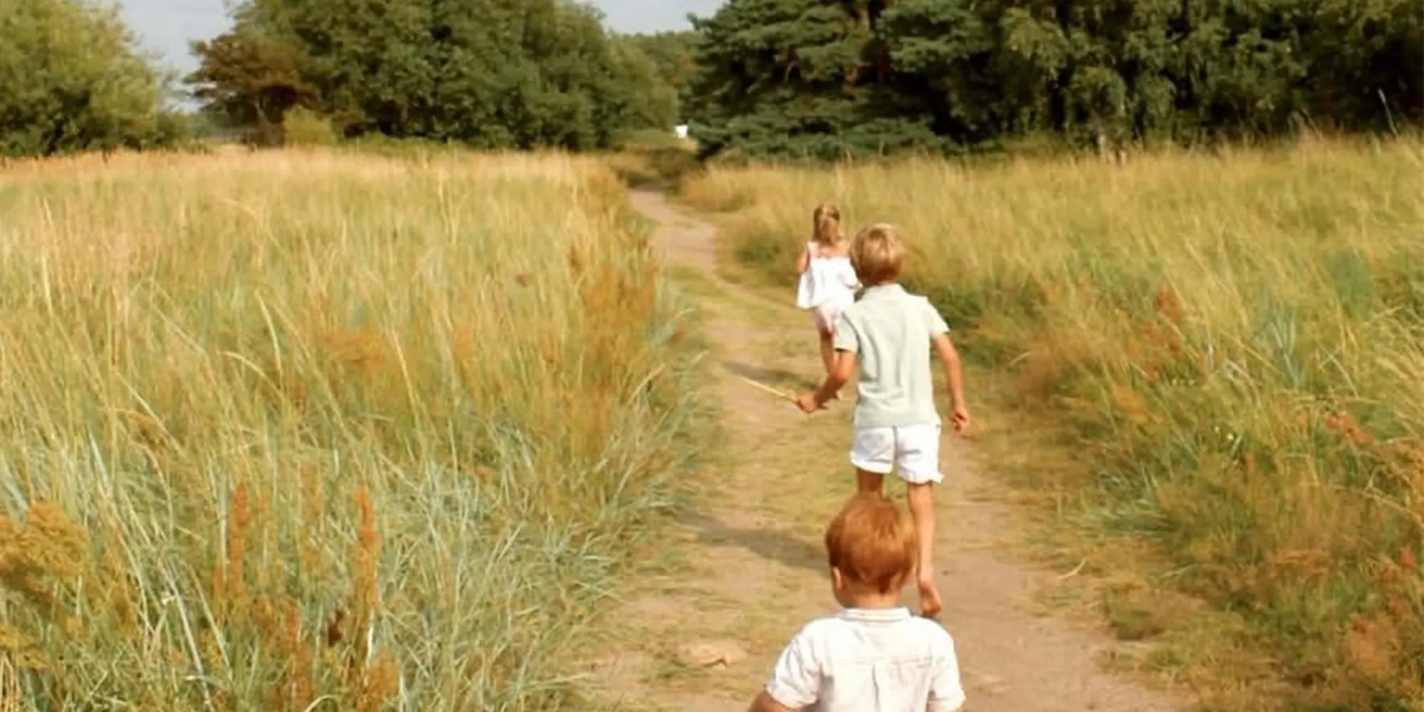 Barn springer i sommarkläder på grusväg