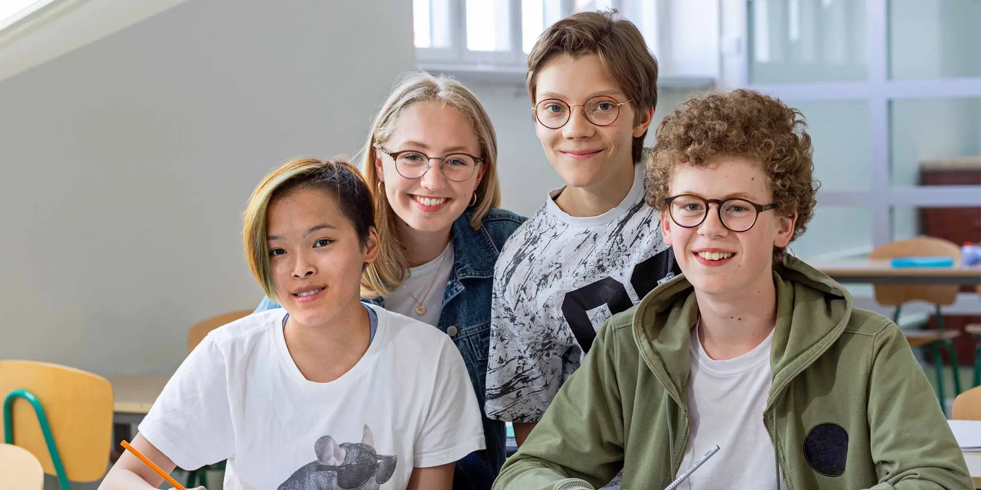 Glada elever sitter i en sal och ler in i kameran.