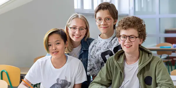 Glada elever sitter i en sal och ler in i kameran.