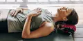 Kvinna ligger på rygg på en yogamatta med ögonen slutna och händerna vilande på mage och bröst.