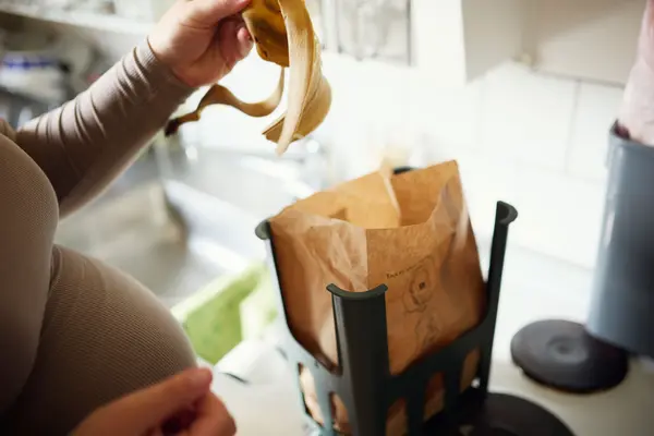 Person slänger bananskal i kompost