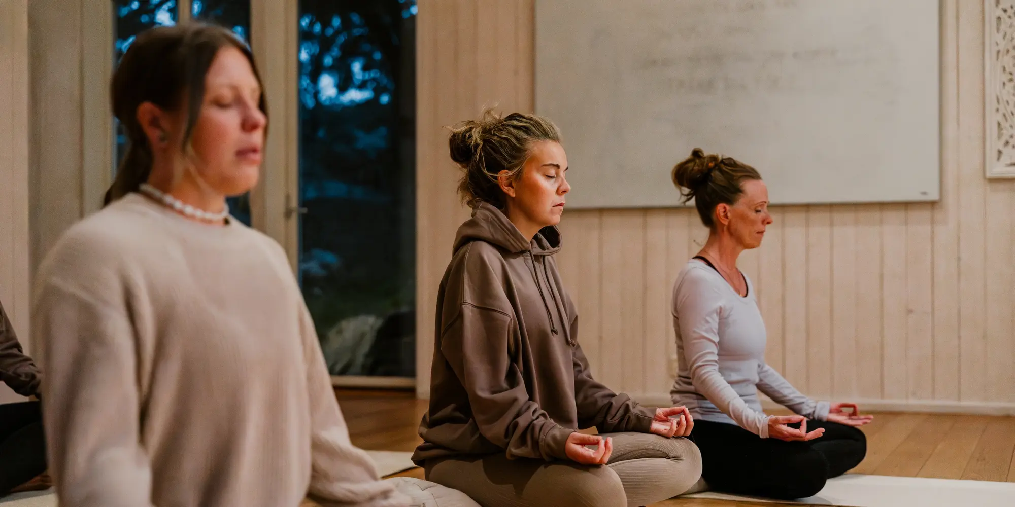 Personer sitter tillsammans på golvet och gör yoga i en sal