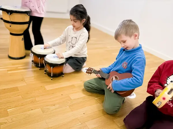 Barn sitter på golvet och spelar olika instrument