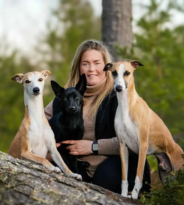 Kursledare Karolin poserar med tre hundar i skogsmiljö