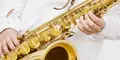 Närbild på en person som spelar saxofon, iklädd vit skjorta