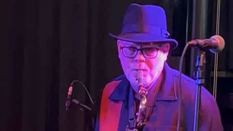 Man i hatt spelar saxofon