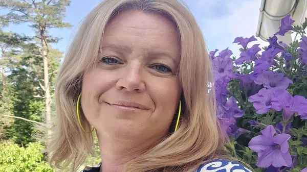 Kursledare Josefine Malmer är fotograferad utomhus med blommor i bakgrunden