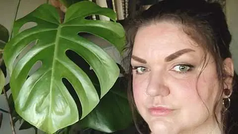 Linda Björnsdotter Gustavsson står vid en grön växt