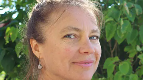 Kursledare Miriam Remdahl tittar in leendes i kameran och i bakgrunden är det gröna löv.