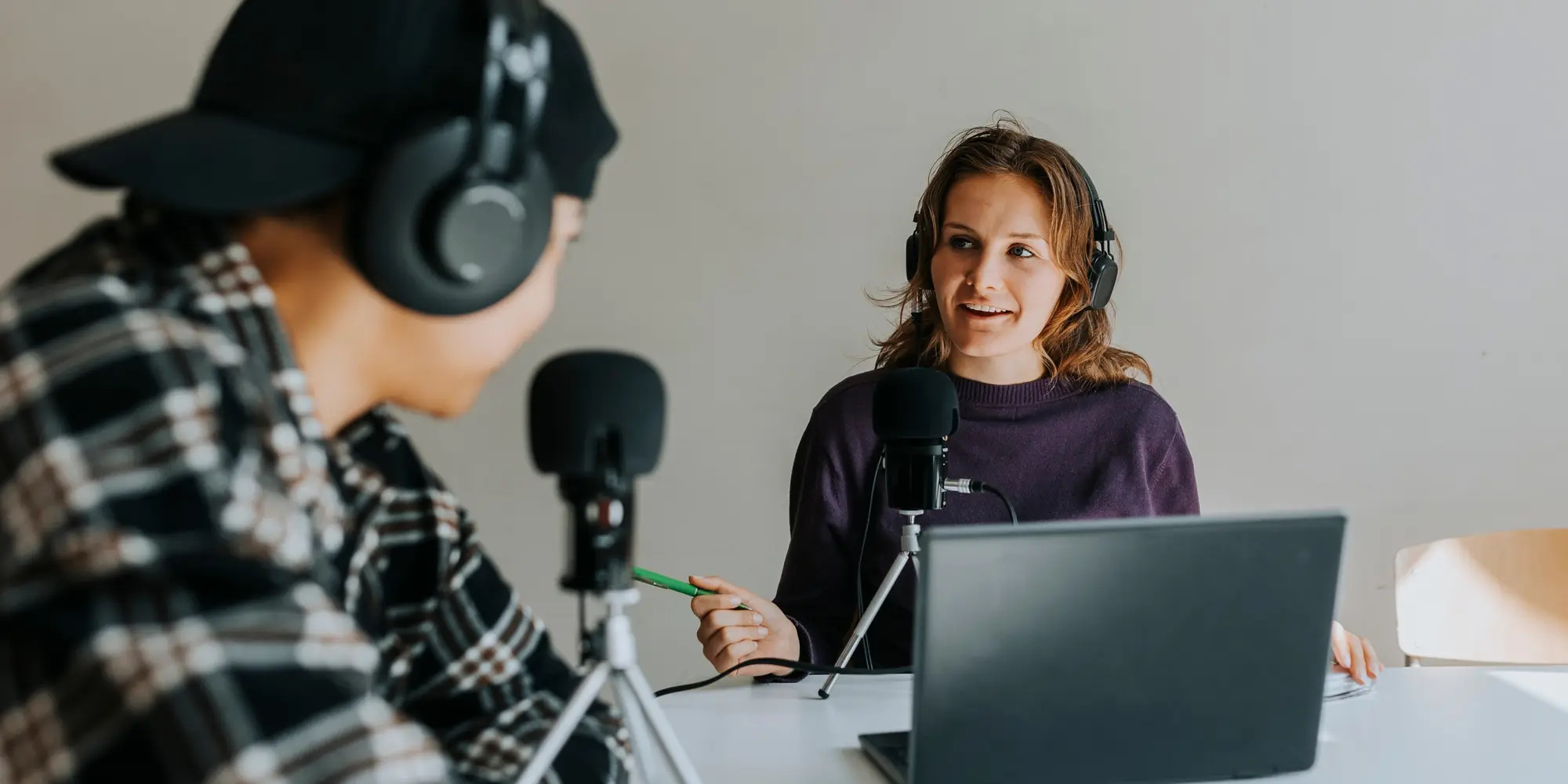 Två personer spelar in podd och pratar i mikrofon