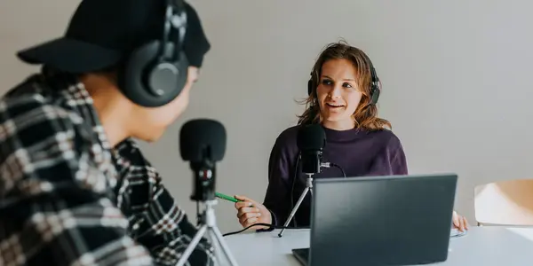 Två personer spelar in podd och pratar i mikrofon