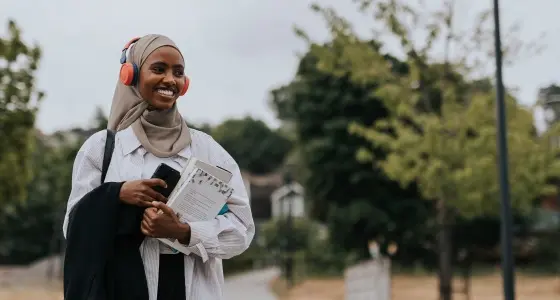 Kvinna med hörlurar och böcker i händerna