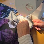 Händer syr tyg i en symaskin i Falkenhus Syateljé i Falkenberg.