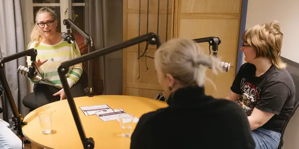 Tre personer talar i en mikrofon och spelar in en podd
